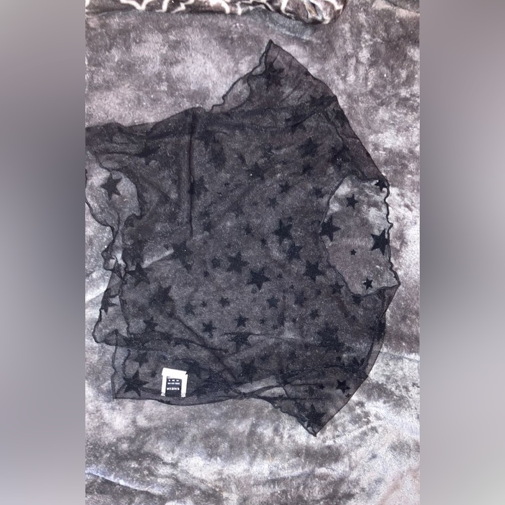 A black see through crop top with non see through stare. The neckline is wavy.